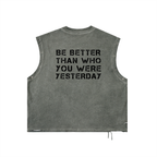 A sleeveless cropped tank top in a washed charcoal gray color, featuring the phrase 'BE BETTER THAN WHO YOU WERE YESTERDAY' printed in black block letters across the back. The garment is displayed flat against a solid white background.