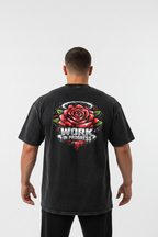A black acid-wash t-shirt shown from the back, featuring a graphic of a red rose with green leaves and the text 'WORK IN PROGRESS' in white and red.